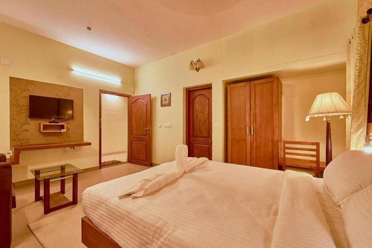 A bedroom with a bed, a TV, a desk, a chair, and a wardrobe.