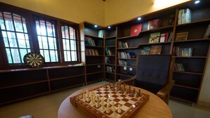 A room with a chessboard, bookshelves, and a dartboard. - Ushasree Wayanad Resort by VOYE HOMES (Sulthan Bathery)