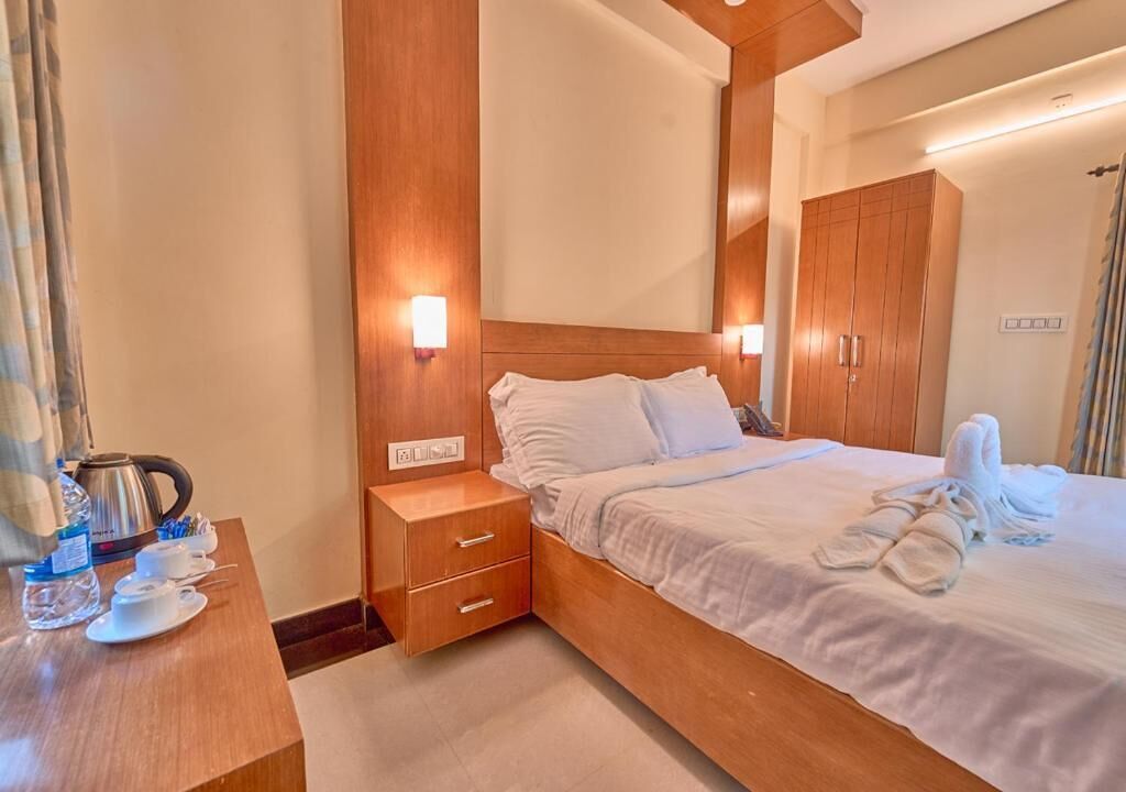 A hotel room with a wooden bed, bedside tables, a mirror, and a wardrobe.