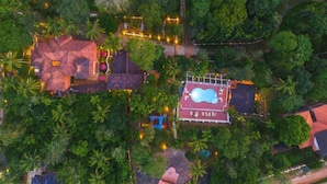 An aerial view of a resort with a swimming pool, multiple buildings, and surrounding greenery. - Ushasree Wayanad Resort by VOYE HOMES (Sulthan Bathery)