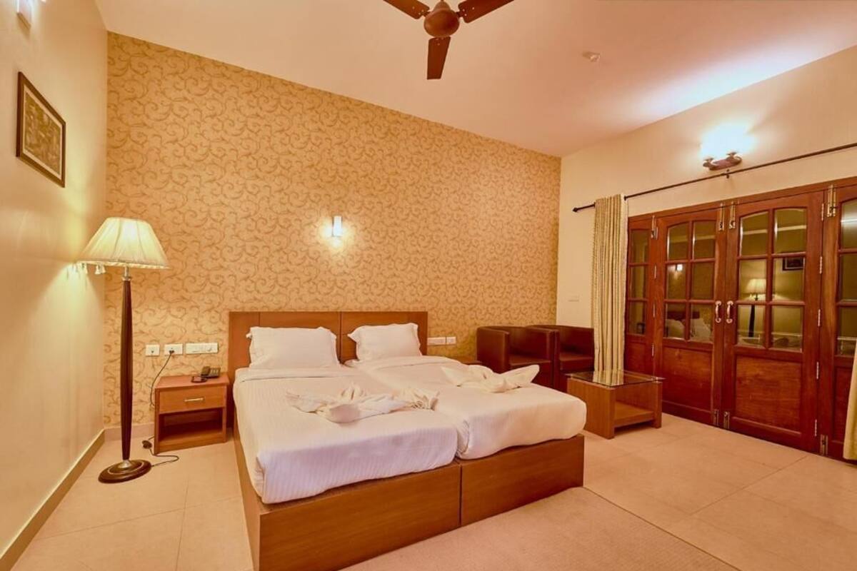 A hotel room with a large bed, a desk, a wardrobe, and a ceiling fan.