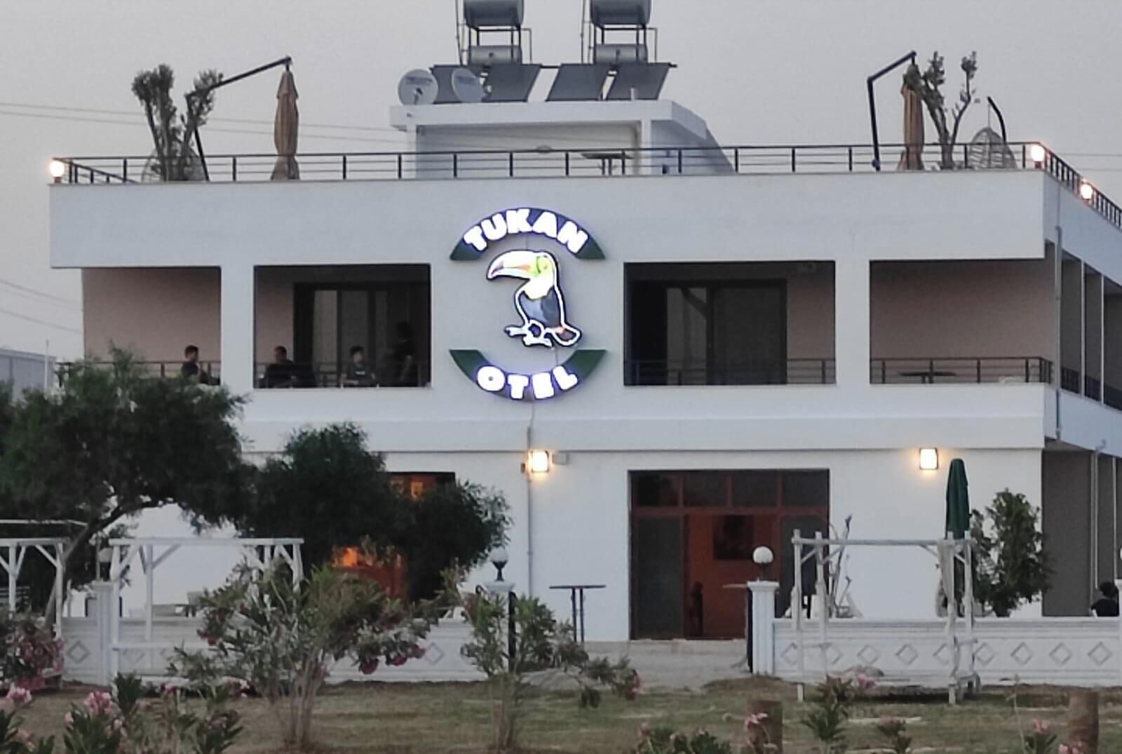 Um edifício moderno com uma placa grande exibindo 'TUKAM OIL' e um logotipo com um pássaro.