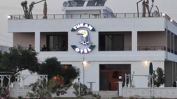 Um edifício moderno com uma placa grande exibindo 'TUKAM OIL' e um logotipo com um pássaro.