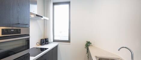 A modern kitchen with a built-in oven, a window, and a sink.