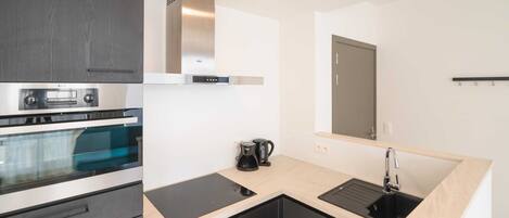 A modern kitchen with a built-in oven, a coffee maker, and a sink.