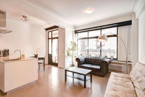 A modern living space with a kitchen island, a sofa, a coffee table, and a large window with a view. - Family Retreat With Balcony in Meir (Antwerp)