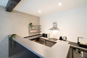 A modern kitchen with a built-in dishwasher, a microwave, a coffee maker, and a sink. - Antwerp Central 1br/7p Apartment (Antwerp)