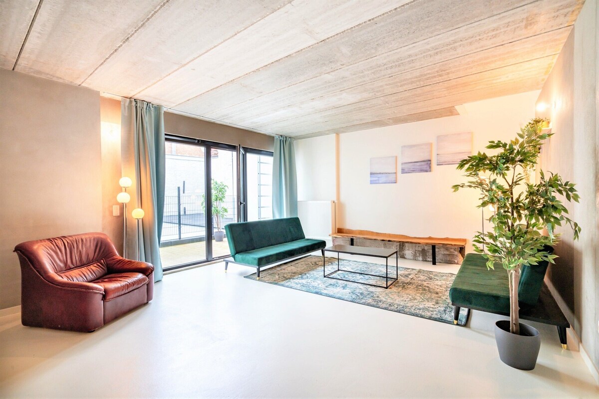 A modern living room with a leather sofa, a green sofa, a coffee table, and a potted plant.