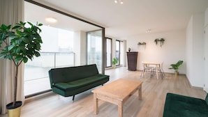 Una sala moderna con un sofá verde, una mesa de centro de madera y un comedor con una mesa pequeña y sillas.