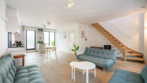 A modern living room with a sofa, a coffee table, and a staircase. - Lighthouse Apartment in Heart of Antwerp (Antwerp)