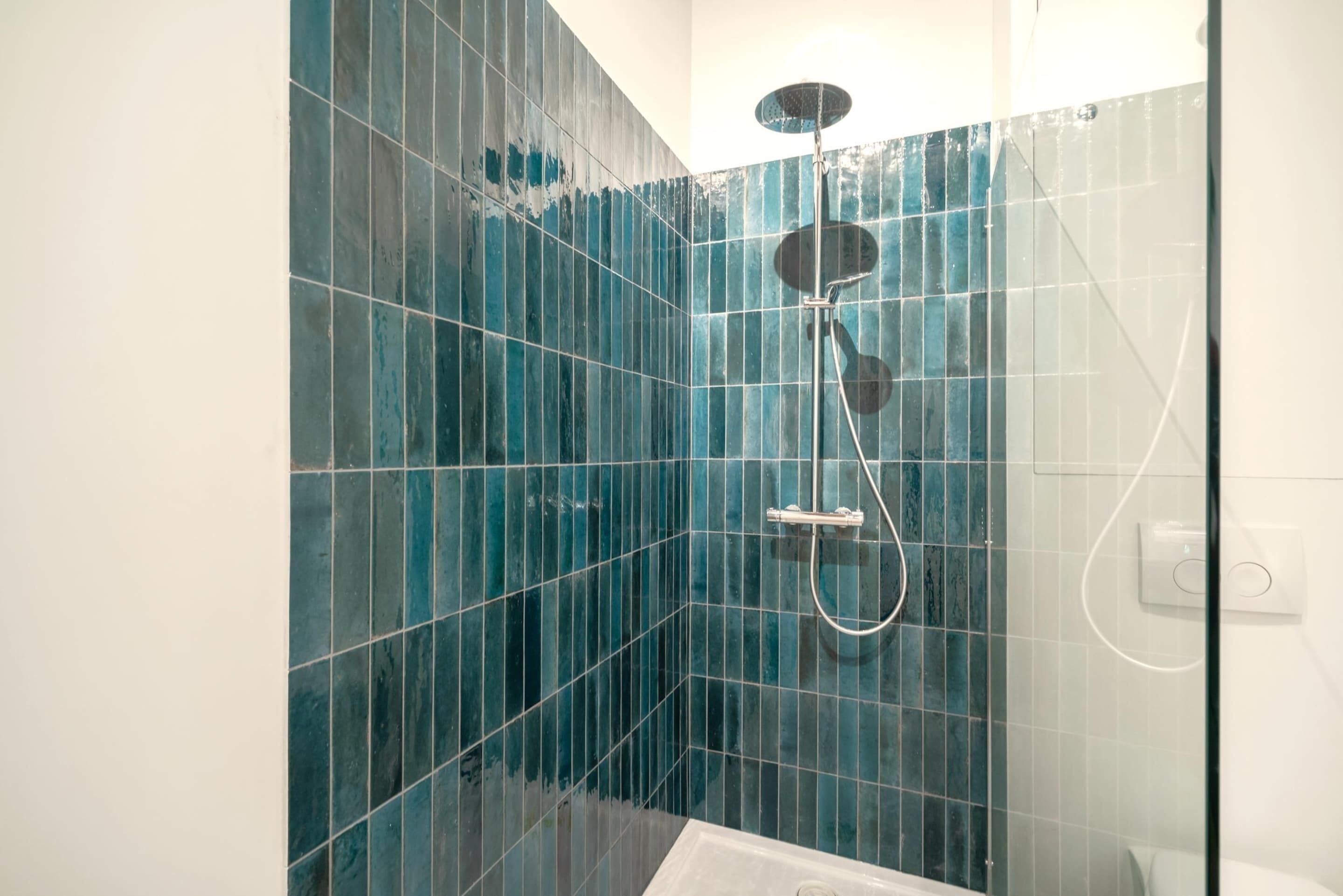 Eine Dusche mit Handbrause und Wandarmatur.
