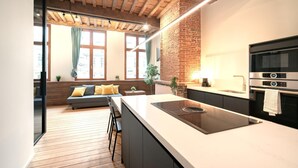 Una cocina moderna con una isla grande, horno integrado y comedor con sofá y sillas.