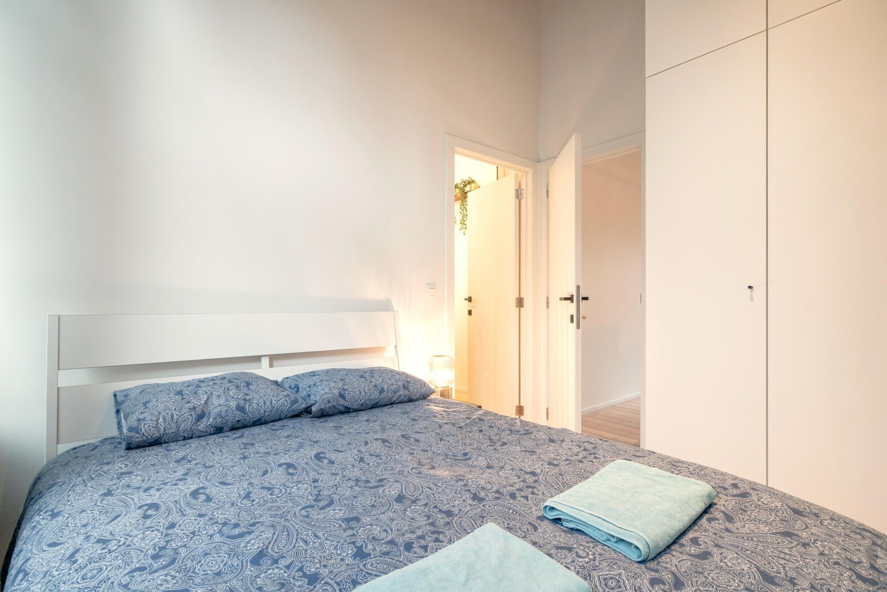 Ein Schlafzimmer mit Bett, Nachttisch, Kleiderschrank und einer Tür zu einem anderen Raum.
