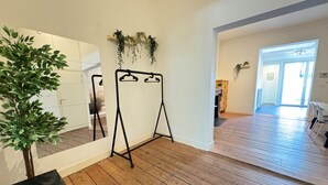 A room with wooden flooring, a black metal swing set, a potted plant, and a mirror on the wall. - Antwerp Old Town 2-bedroom (Antwerp)