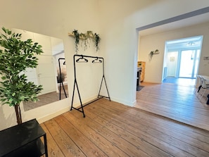 A room with wooden flooring, a black metal swing set, a potted plant, and a mirror on the wall. - Antwerp Old Town 2-bedroom (Antwerp)