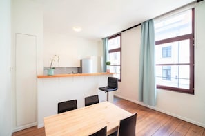 A modern kitchen with a wooden countertop, a chair, and a dining table. - Old Town Lodge Antwerp Apartment (Antwerp)