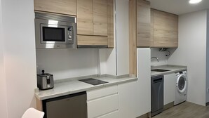 A modern kitchen with wooden cabinets, a microwave, a toaster, a dishwasher, and a sink.