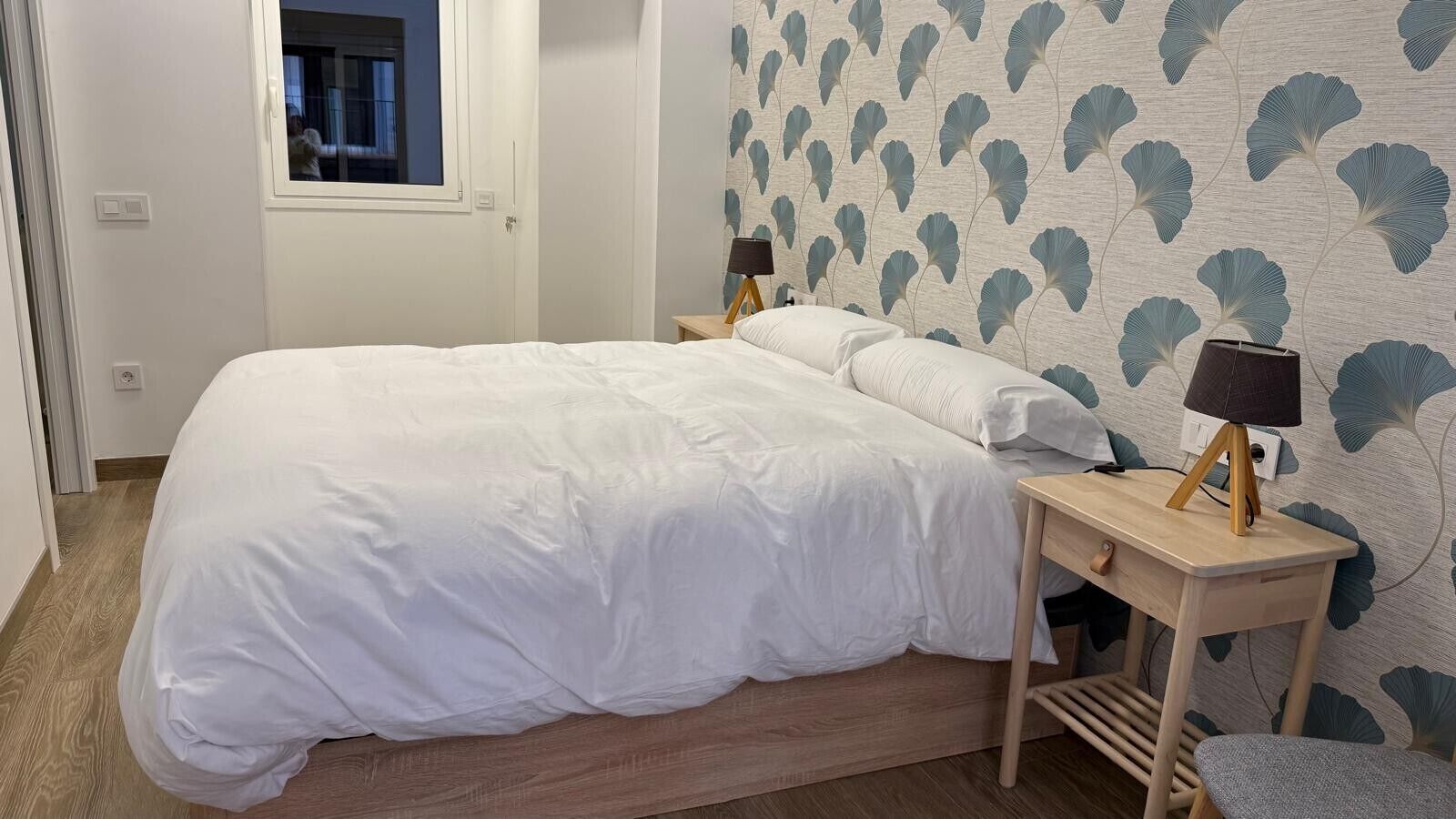 Ein Schlafzimmer mit einem Bett, Nachttischen, einer Lampe und einem Fenster.