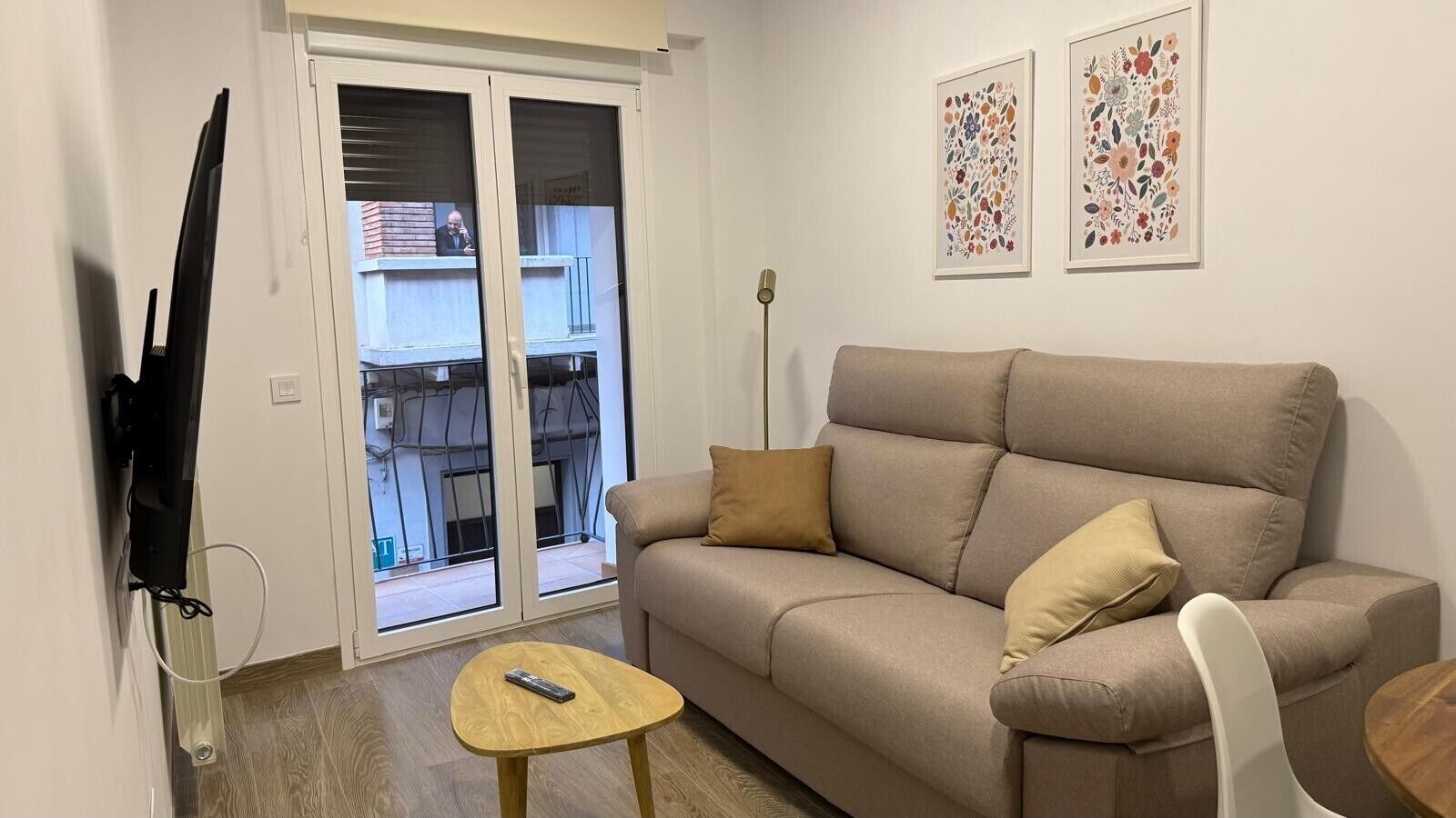 Un salon avec un canapé, une table basse, un téléviseur et un balcon offrant une vue agréable.