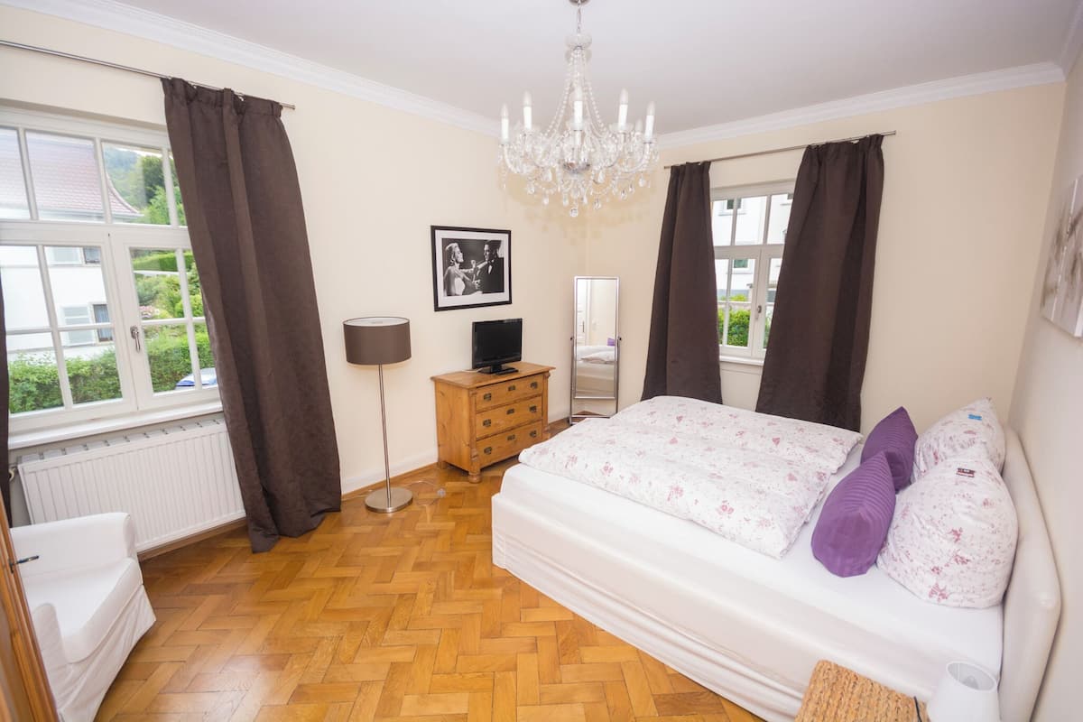 A bedroom with a bed, dresser, and a television.
