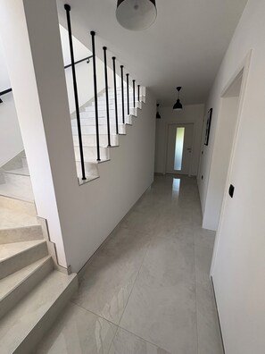 A modern interior with a staircase, a hallway, and a door leading to another room. - Cozy family apartment in quiet surroundings close to the sea (Kostrena)
