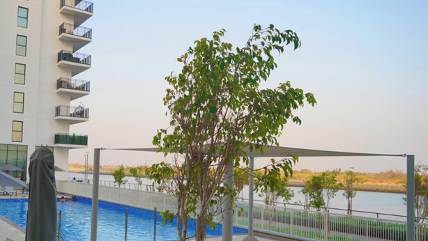 A swimming pool with a view of a river and a building with balconies.
