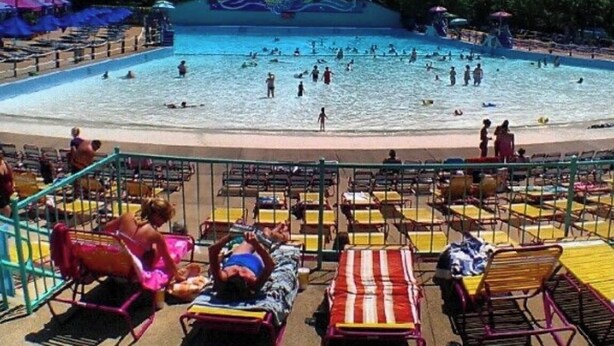 Ein Poolbereich mit mehreren Schwimmbahnen, Liegestühlen und einer schattigen Sitzgelegenheit.
