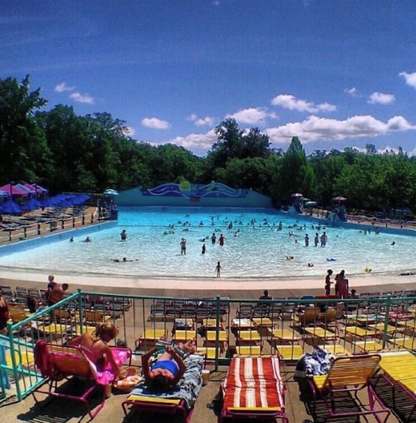 A pool area with multiple swimming lanes, lounge chairs, and a shaded seating area.