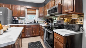 A kitchen with wooden cabinets, a stainless steel refrigerator, a microwave, an oven, and a coffee maker.