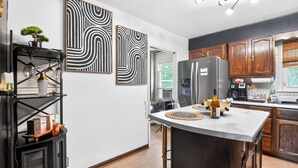 Eine moderne Küche mit einer zentralen Kochinsel, Holzschränken und abstrakter Wandkunst.