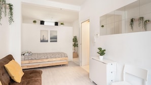 Un dormitorio moderno con cama, sofá, escritorio y espejo.