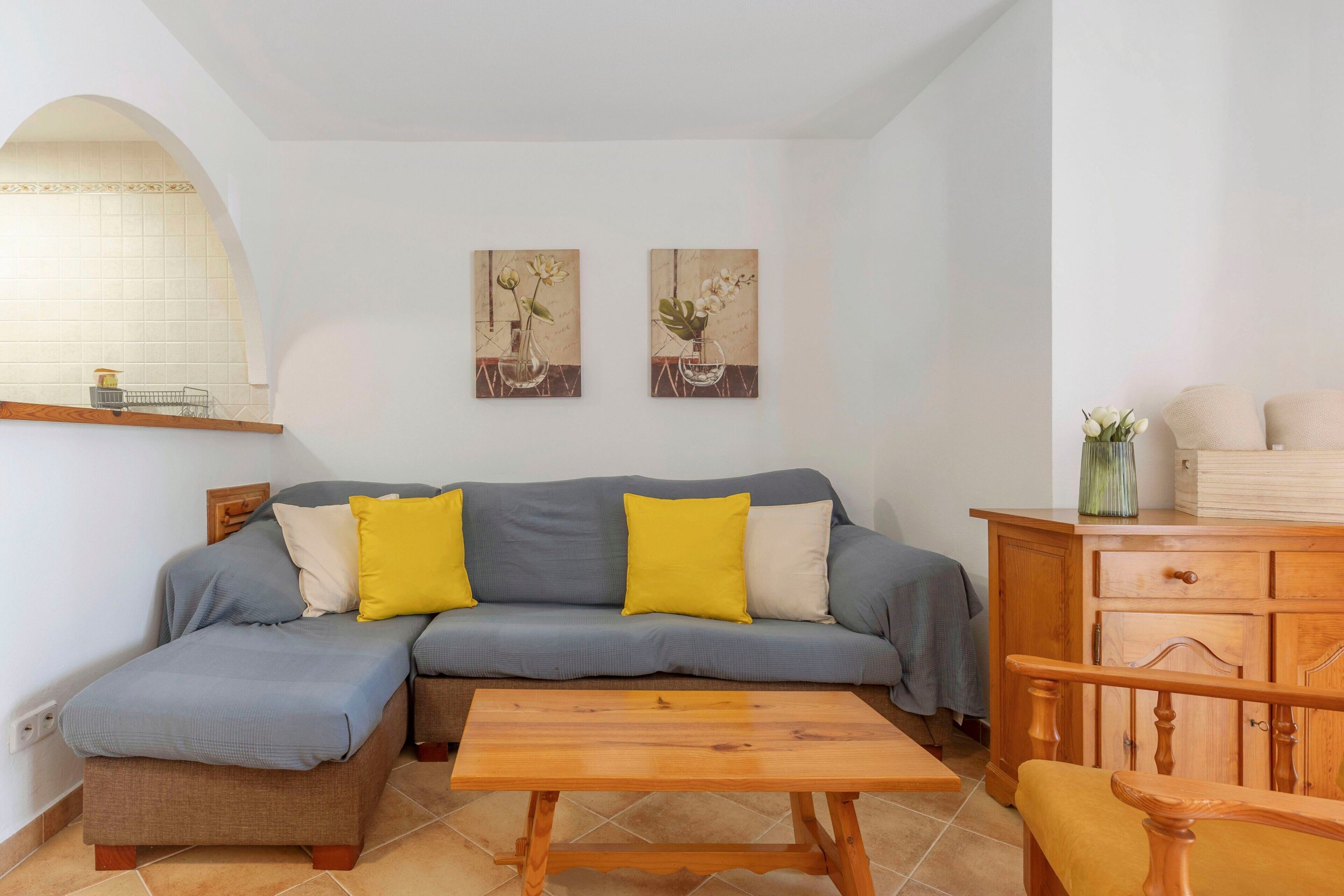 A living room with a sofa, a wooden coffee table, a wooden cabinet, and two wall-mounted paintings.