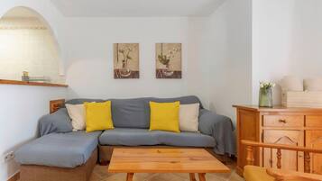 A living room with a sofa, a wooden coffee table, a wooden cabinet, and two wall-mounted paintings.