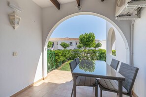 Un patio con tavolo e sedie, un arco, vista su un edificio e un cancello verde.