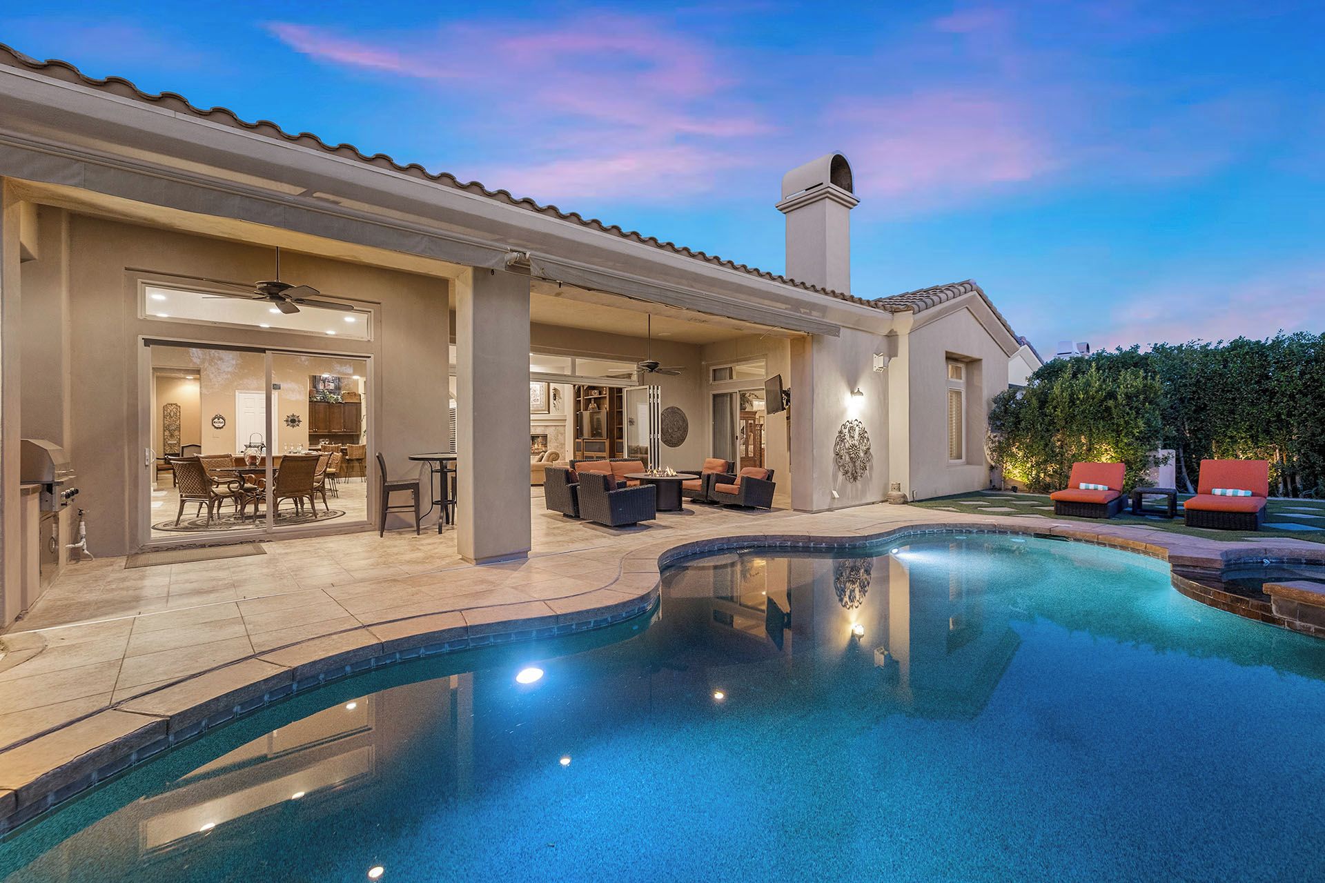 A poolside area with a covered patio, outdoor furniture, and a swimming pool.