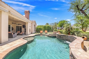 A swimming pool with a stone edge, outdoor seating, and a covered patio area. - Veranda - On the Greg Norman Course at PGA! (La Quinta)