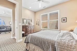 A bedroom with a bed, dresser, and a large window with blinds. - Veranda - On the Greg Norman Course at PGA! (La Quinta)