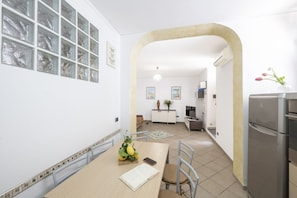 A modern kitchen with a dining area, a refrigerator, and a view into the living room. - Comfortable Praiano Stay with Partial Sea View by Maravista (Praiano)