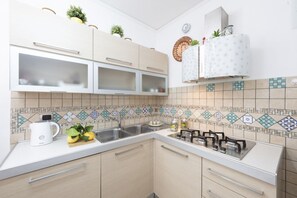 A modern kitchen with a microwave, stove, and cabinets. - Comfortable Praiano Stay with Partial Sea View by Maravista (Praiano)