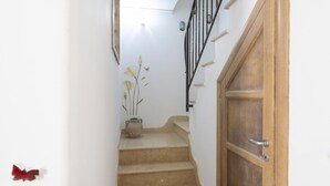 Una escalera con una puerta de madera y un jarrón con flores.