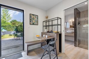 Eine moderne Küche mit Glastür zu einer Terrasse, einem Essbereich mit einer Bank und einem an der Wand montierten Regalsystem.