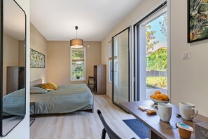 A modern bedroom with a bed, a desk with a bowl of fruit, and a view through a sliding door. - Room - Vent d’Ouest with Private Terrace, 20min from Puy du Fou (Saint-Prouant)