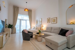 A modern living room with a sofa, armchair, coffee table, and a TV on a cabinet.