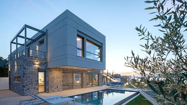 A modern two-story house with a swimming pool, stone facade, and glass windows.