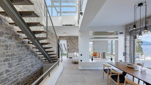A modern interior with a staircase, a dining area, and a view of the outdoors.