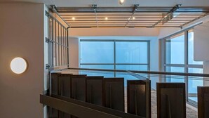 A modern interior with a staircase, large windows, and a ceiling with recessed lighting.
