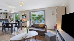 A modern living room with a sofa, dining table, and TV. - Holiday Home "Maison Vent d’Ouest" with Private Terrace and Wi-Fi in La Tranche sur Mer (La Tranche-sur-Mer)