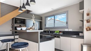 A modern kitchen with a built-in microwave, oven, and sink, a bar area with stools, and a large window providing natural light. - Holiday Home "Maison Vent d’Ouest" with Private Terrace and Wi-Fi in La Tranche sur Mer (La Tranche-sur-Mer)