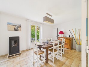 Ein Essbereich mit Tisch für vier Personen, einem Kamin, einem Fenster mit Vorhängen und einem Gemälde an der Wand.
