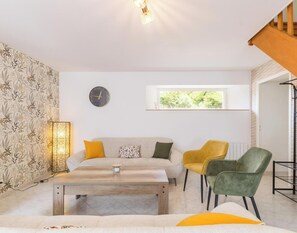 A modern living room with a sofa, chairs, a coffee table, a clock, and a window.